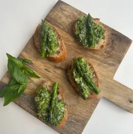 Four crostini topped with pesto and asparagus