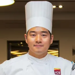 chef bobby yoon in chef's toque and culinary school jacket