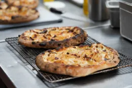 Two tarte flambées cooling on baking rack.