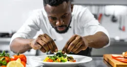 A chef skillfully arranges food on a plate, showcasing culinary expertise and attention to detail.