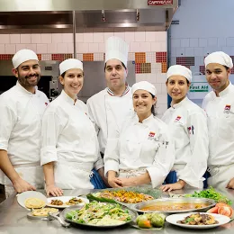 An ICE chef instructor poses with culinary arts students at the Institute of Culinary Education