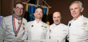 Four chefs in their chef whites, one wearing a medal- photo credit Lydia Lee Photo