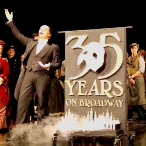 The Broadway cast of The Phantom of the Opera stands next to Chef Jürgen David's 35th anniversary cake