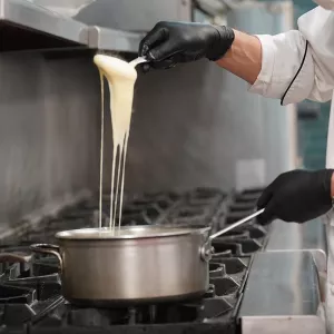 A hand scoops cheesy pommes aligot from a pot.