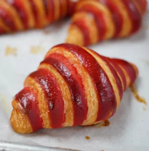 A red-striped croissant sits on a piece of white parchment paper