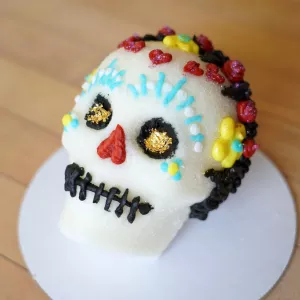 A sugar skull decorated with blue, yellow, red and black icing