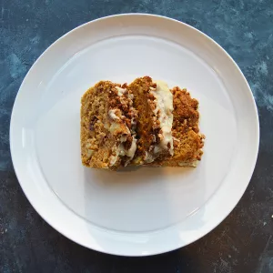 A slice of banana bread sits on a white plate on a blue table