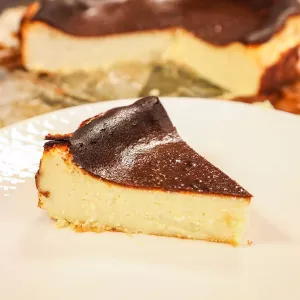 A piece of burnt Basque cheesecake on a white plate made using Chef Eric's Basque cheesecake recipe