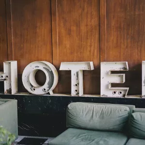 Hotel lettering sign over a bed - Photo by Bill Anastas via Unsplash