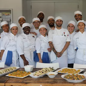 A culinary class smiles with their plated dishes