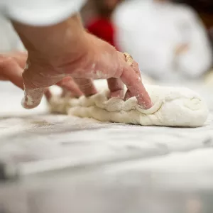 A pastry chef kneads dough to make bread.