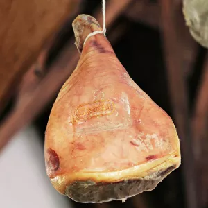 A cured ham leg hangs upside down on a string