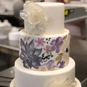 A pulled sugar flower on a hand-painted cake