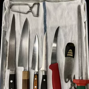 knives and kitchen tools sit on a white towel