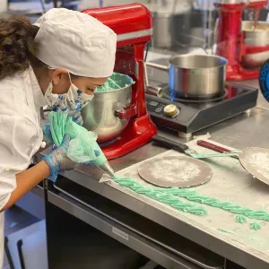 A Pastry & Baking Arts student practices piping with a face mask and gloves.