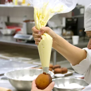 pastry student piping cream into a doughnut