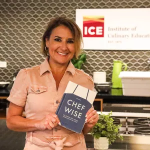 Shari Bayer smiles while holding a copy of her book "Cherfwise"