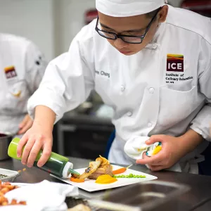 A culinary student plates a dish at ICE