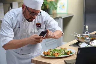 A student takes a photo of a dish for ICE's online culinary program