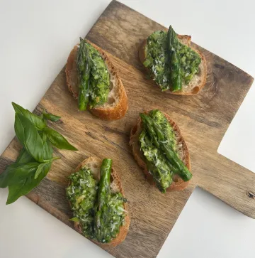 Four crostini topped with pesto and asparagus