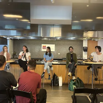 5 panelists sit on chairs in a row