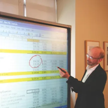 Man wearing suit shows financial forecast spreadsheet to potential food product investors.