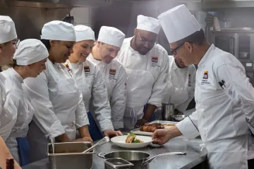 ICE students plating in the kitchen with Chef Roger. 