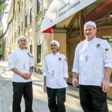 ICE students stand outside LA campus entrance in culinary chef whites.