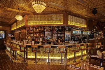 Inside the bustling, brightly lit Thai Diner in Nolita, NYC, featuring woven bamboo ceilings and colorful, eclectic diner decor.