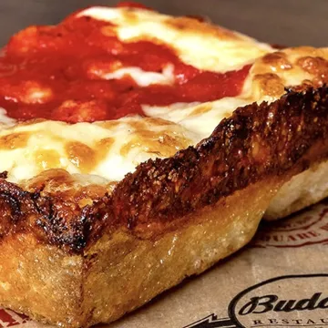 Thick corner square slice of Detroit-style pepperoni pizza with crispy edges and burnt cheese.