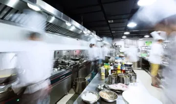 busy professional kitchen where chefs are preparing mise en place for dinner service
