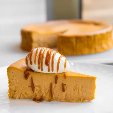 Slice of Pumpkin Basque Cheesecake topped with whipped cream and caramel