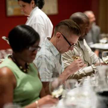 Wine student assessing aroma of red wine in glass at recreational wine class.