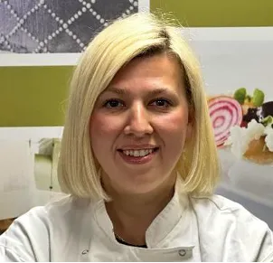 ICE Chef-Instructor Marina Cope smiles at the camera wearing chef whites.