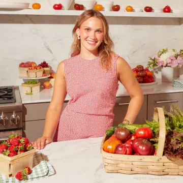 Photo of ICE alumni Meredith Hayden as she stands in a kitchen with fruit. 