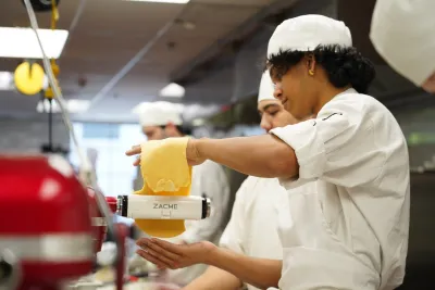 Student rolling pasta dough.