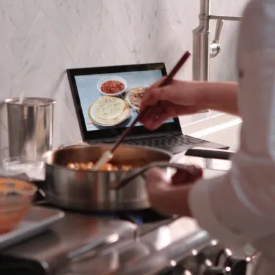 Person cooking chickpea curry with a laptop