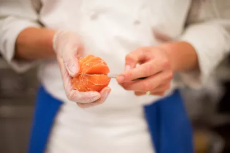 A culinary student is segmenting an orange for mise en place