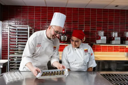 an Advanced Pastry & Baking Technique instructor and student work on preparing Bonbons 