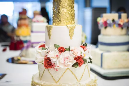 A white and gold foil cake with gumpaste flowers from the ICE Professional Cake Decorating Program