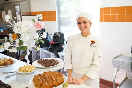 An ICE student smiles at a pastry buffet