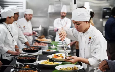 A student in ICE LA's culinary career training program takes food from a buffet prepared by other ICE students