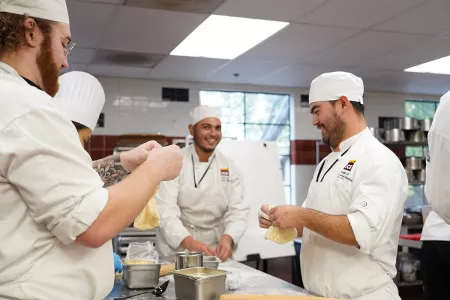 ICE students smile while shaping dough as part of the culinary career training program