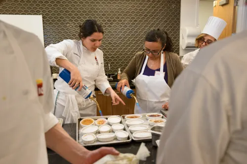 An ICE chef helps a guest work with a torch.