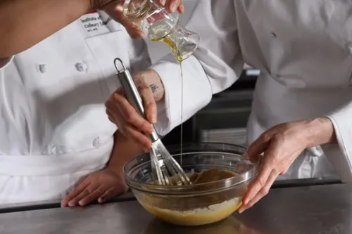 two students from ICE's Culinary Nutrition course add olive oil to a dressing to emulsify