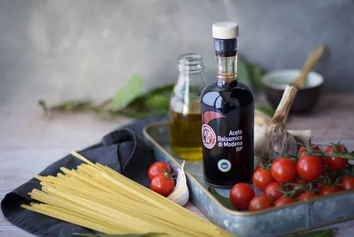 Balsamic vinegar bottle among pasta ingredients.