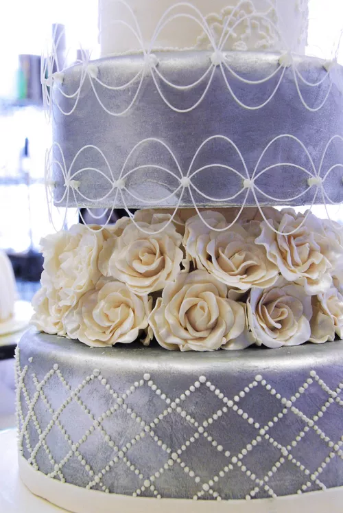 A blue-silver cake with white flowers from the ICE Professional Cake Decorating continuing education Program