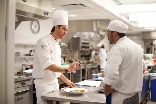 An ICE instructor gives feedback on a dish to an ICE student in the culinary school program.