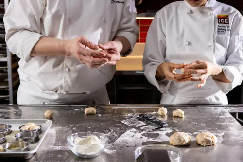 an Adavanced Pastry & Baking Technique student and instructor shape dough with their hands