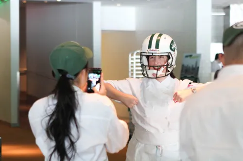 Chefs put on a Jets helmet at a cooking event.